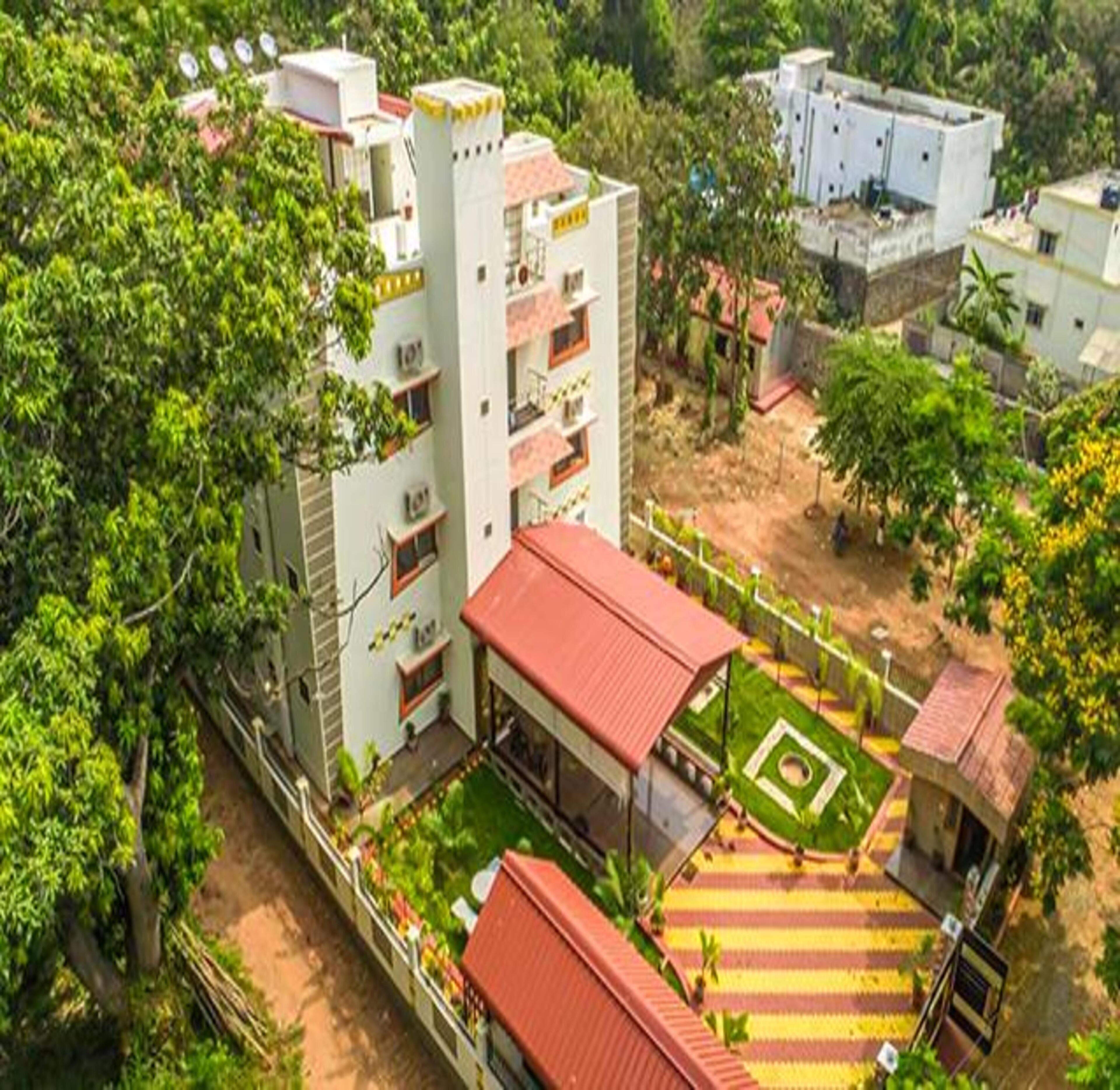 A multi-story building with balconies, surrounded by greenery.
