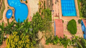 An aerial view of a property with a large rectangular swimming pool, a smaller circular pool, and a circular hot tub. - Fabescape Queens Paradise (Vanur)