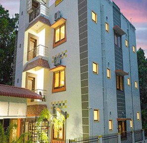Un hotel de varios pisos con balcones, una escalera visible y una entrada con portón.