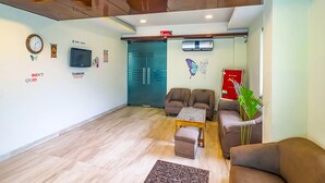 A modern living area with a sofa set, a coffee table, and a small table. - Fabhotel Merriment City (Noida)