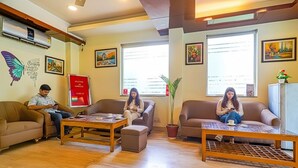 A cozy lobby with three sofas, a coffee table, and a potted plant. - Fabhotel Merriment City (Noida)