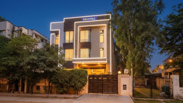 A modern hotel with a flat facade, a gated entrance, and a well-maintained lawn. - Fabhotel Merriment City (Noida)