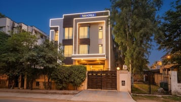 Un hotel moderno con fachada plana, entrada protegida por un portón y césped cuidado.