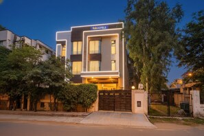 A modern hotel with a flat facade, a gated entrance, and a well-maintained lawn. - Fabhotel Merriment City (Noida)