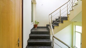 A staircase with a handrail, a wooden door, and a potted plant. - Fabhotel Merriment City (Noida)