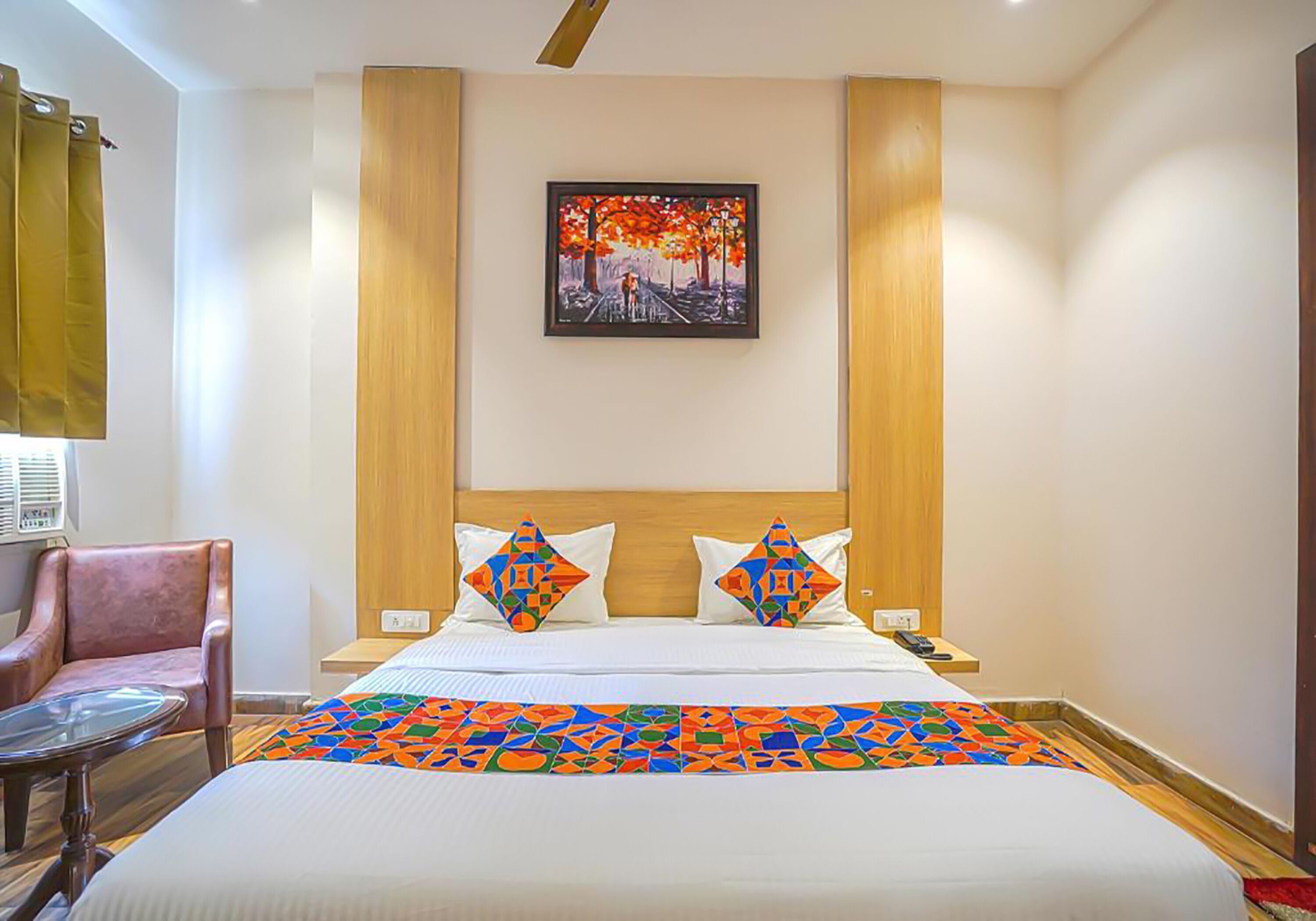 Une chambre d’hôtel avec un lit, une chaise, un tableau au mur et une fenêtre avec des rideaux.