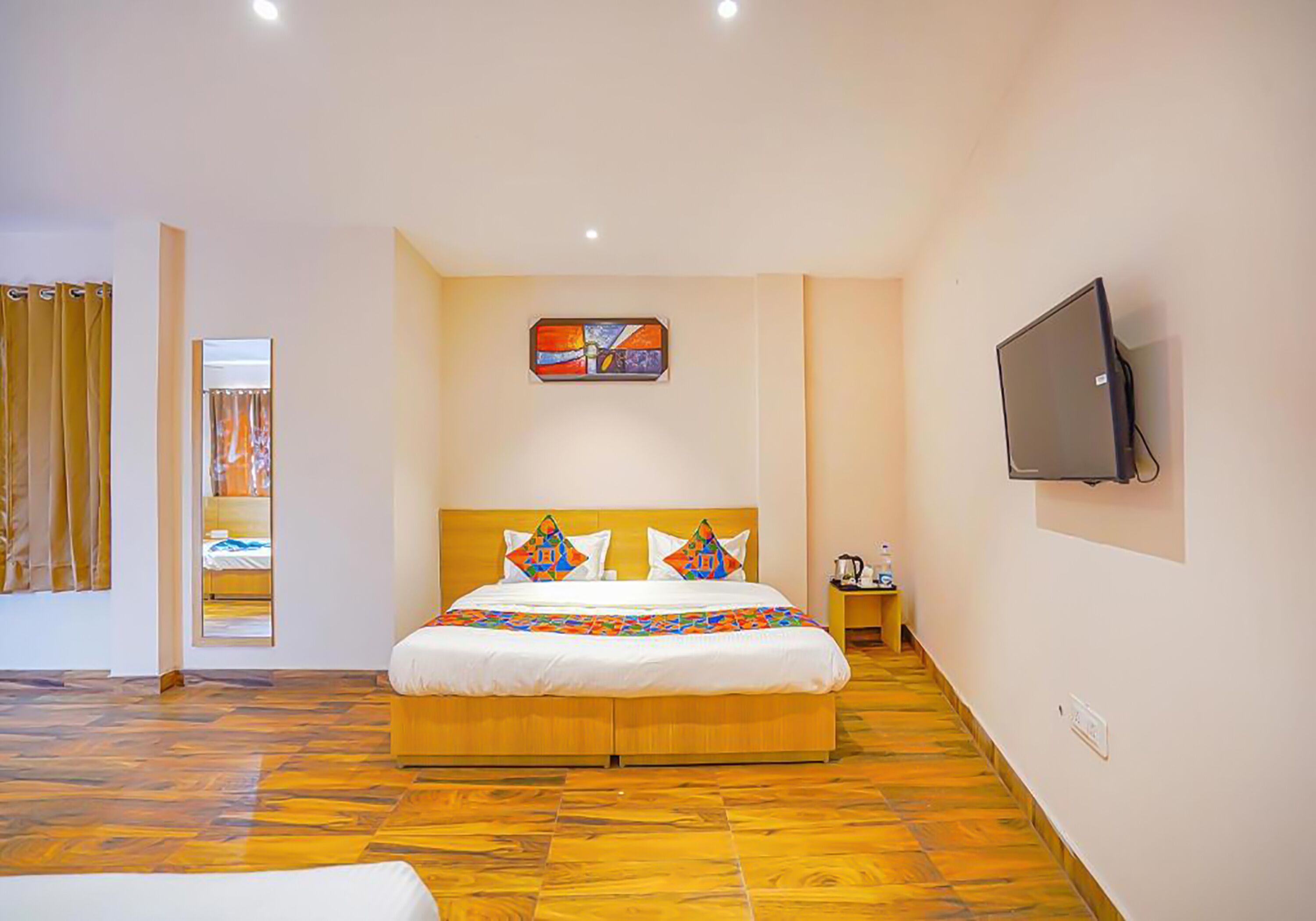 Una habitación de hotel con una cama grande, un televisor montado en la pared y suelo de madera.