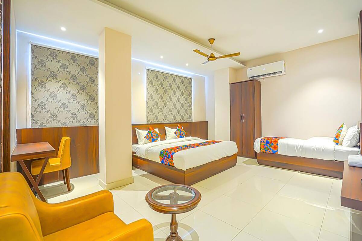 A hotel room with a bed, a desk, a chair, a round table, and a ceiling fan.