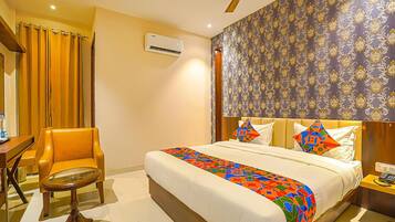 A hotel room with a bed, a chair, a table, and a ceiling fan.