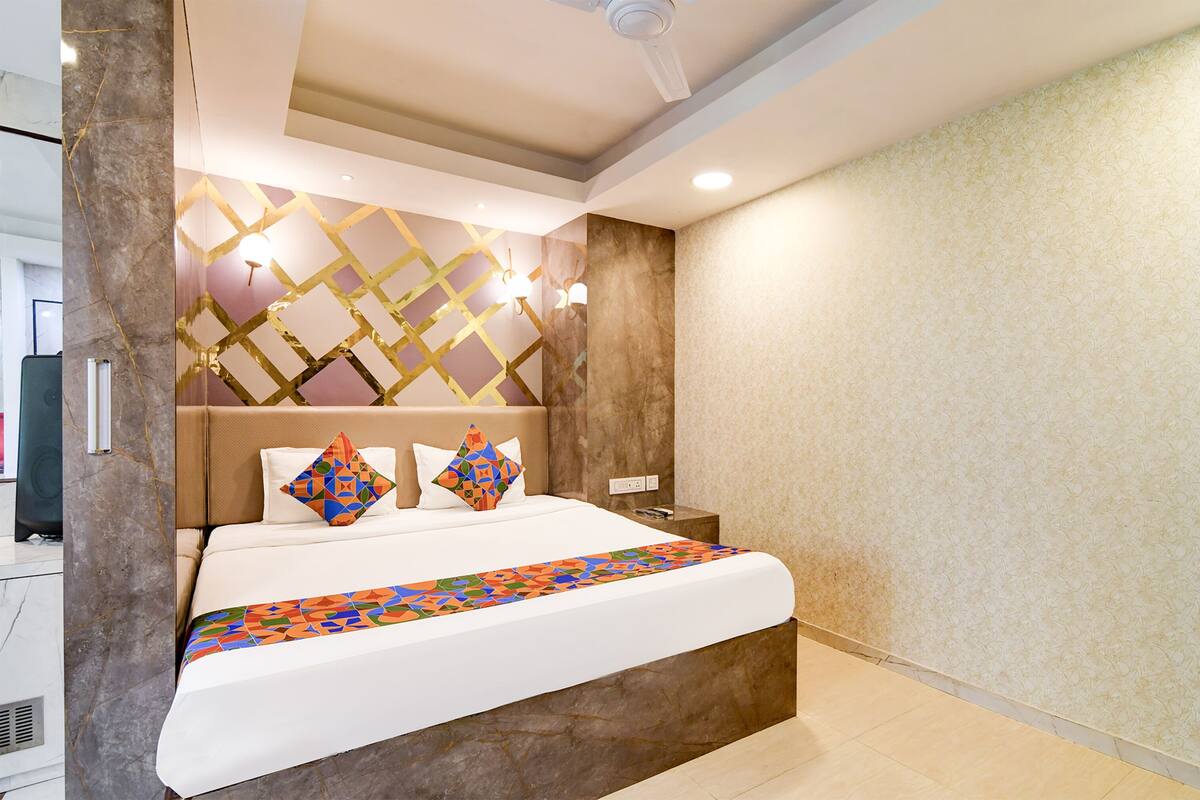 Une chambre d’hôtel moderne dotée d’un grand lit, d’un mur décoratif en marbre et d’une tête de lit à motifs géométriques.
