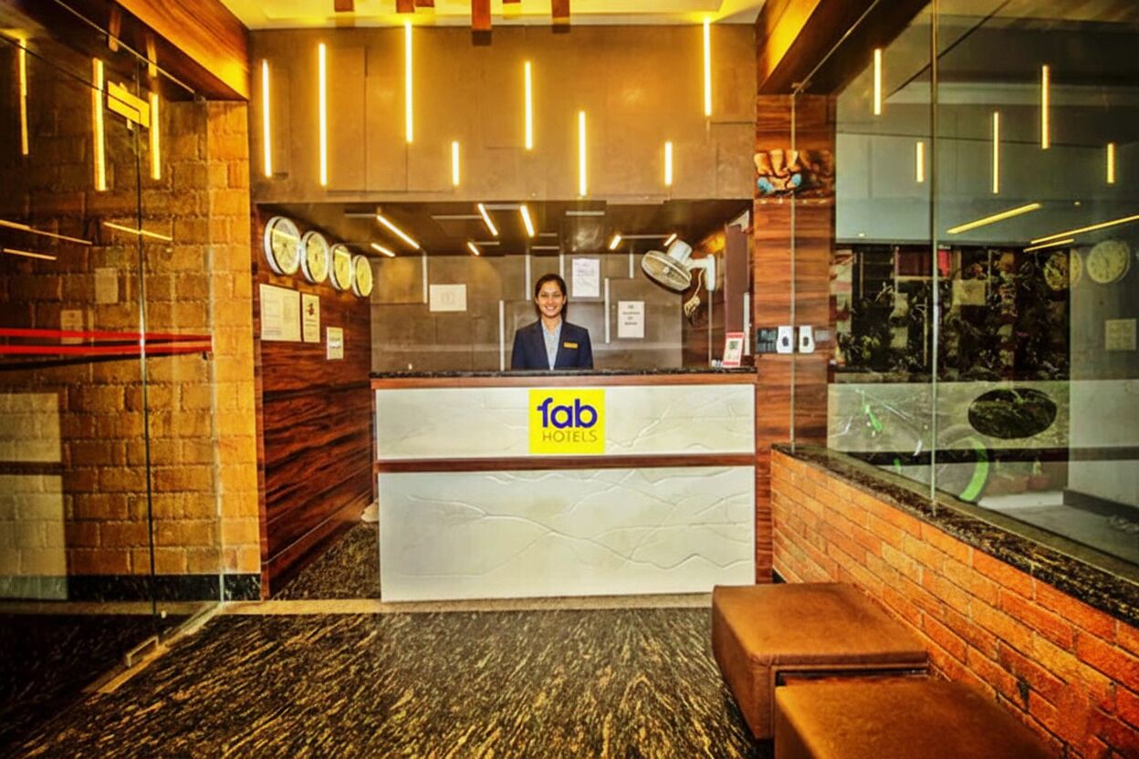 A hotel reception desk with a modern design, featuring a wooden reception area, a glass partition, and a clock on the wall.