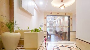 Un hall d’hôtel au design moderne, comprenant un comptoir d’accueil, un espace salon et un motif décoratif sur le sol.