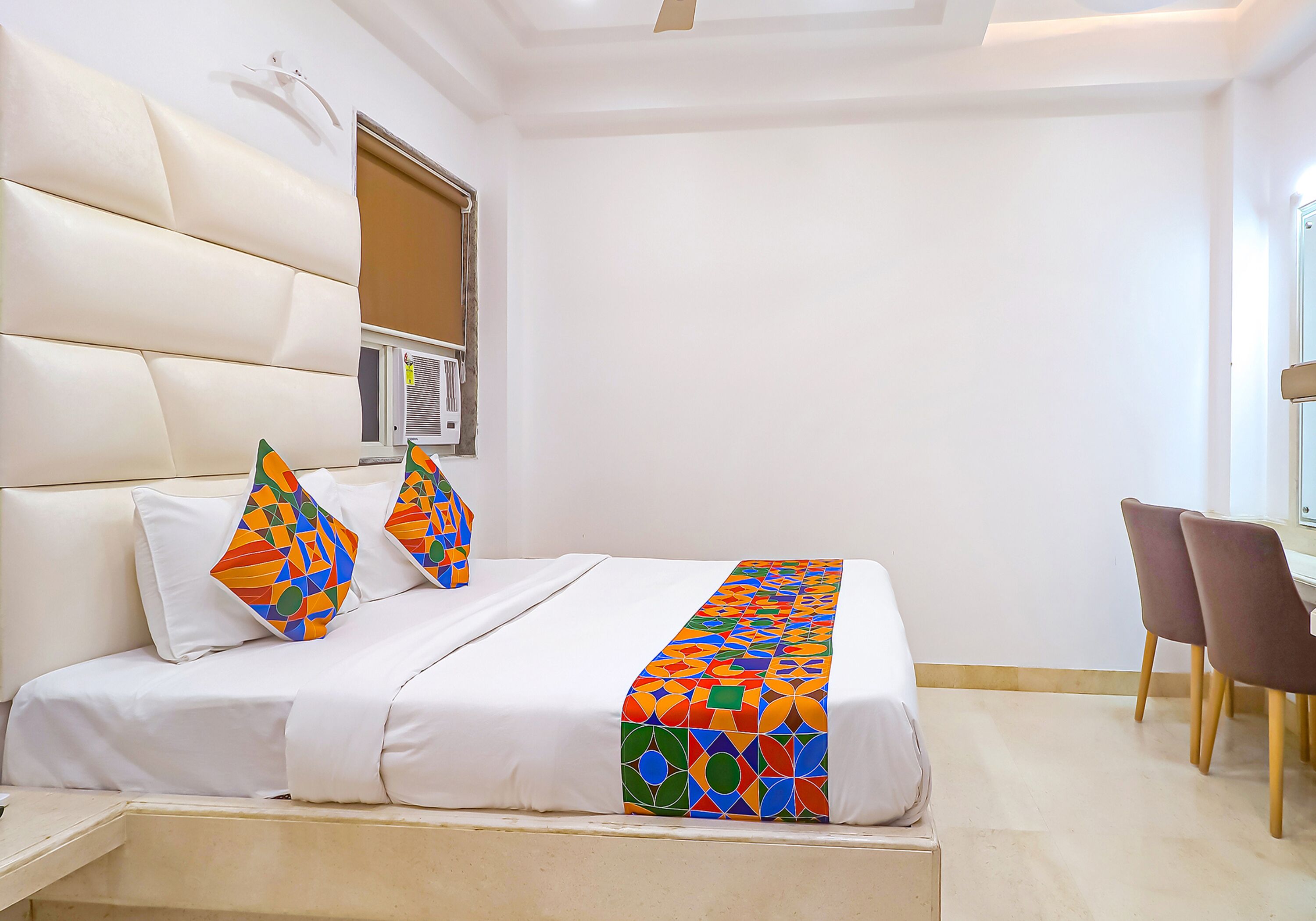 A hotel room with a bed, a window, a desk, and a chair.