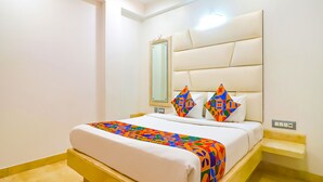 Une chambre d’hôtel comprenant un lit, une table de chevet, une commode, un miroir et un luminaire fixé au mur.