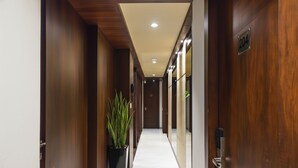 A hallway with wooden doors, a potted plant, and a sign indicating room number 204. - Fabhotel Eros 211 (Bidhannagar)