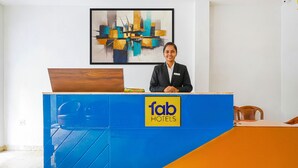 A reception desk with a blue and orange color scheme, a logo for 'fab hotels', and a modern abstract painting on the wall. - Fabhotel Eros 211 (Bidhannagar)