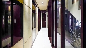 A modern hotel corridor with glass doors, a central white-tiled walkway, and a staircase on the right. - Fabhotel Eros 211 (Bidhannagar)
