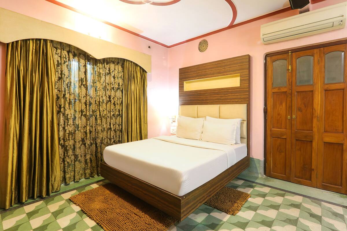 A bedroom with a bed, curtains, a wardrobe, and a patterned floor.