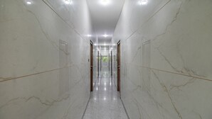 A corridor with marble walls and a shiny floor, leading to a door at the end.