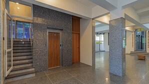 A modern interior with a marble staircase, a wooden door, and a glass elevator.