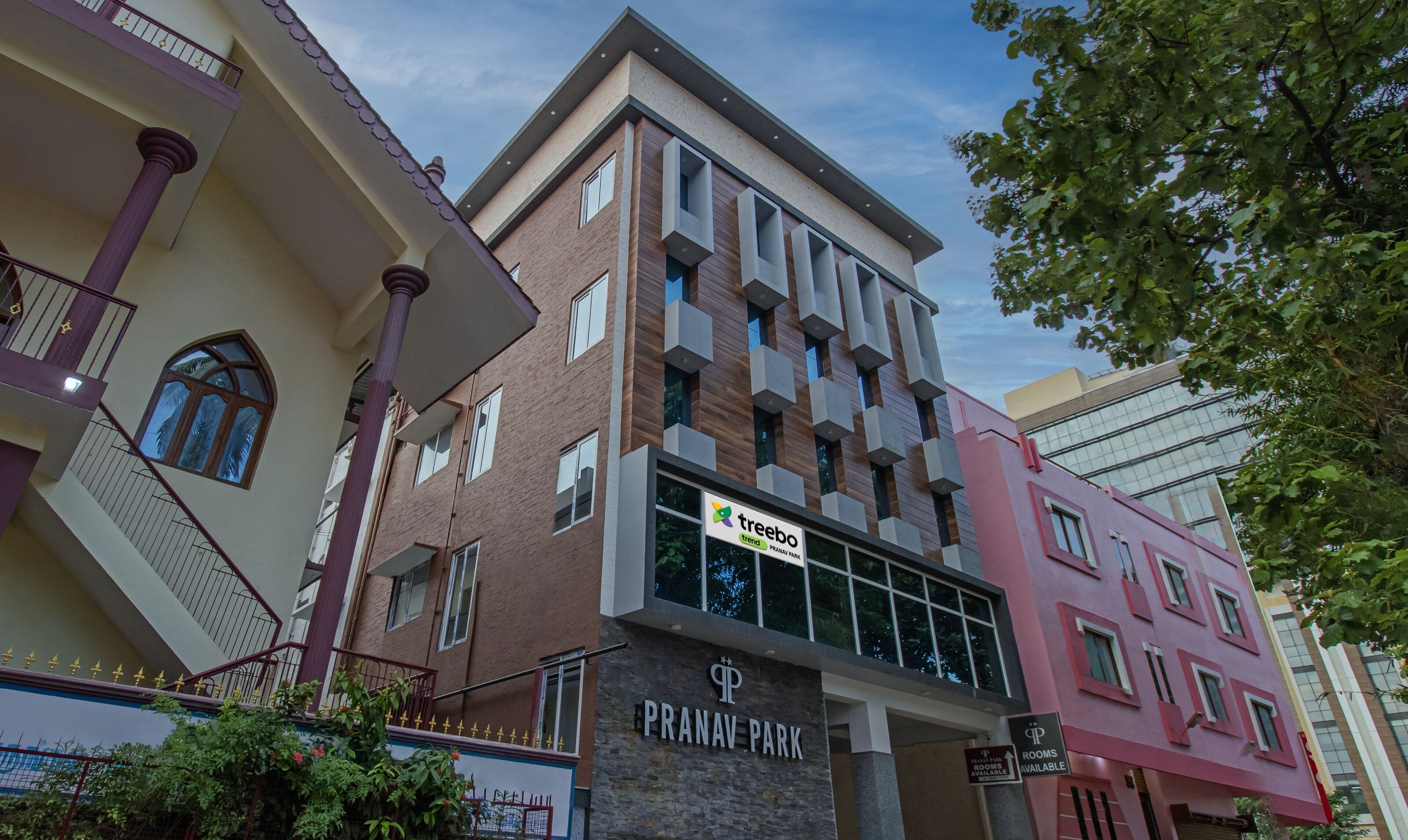 Un hotel con un cartel que indica 'treebo trend' y 'Pranav Park', mostrando habitaciones disponibles.