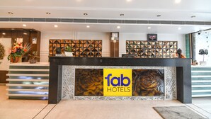 En hotelreception med et 'fab hotels' skilt, et venteområde og en dekorativ væg med geometriske mønstre.