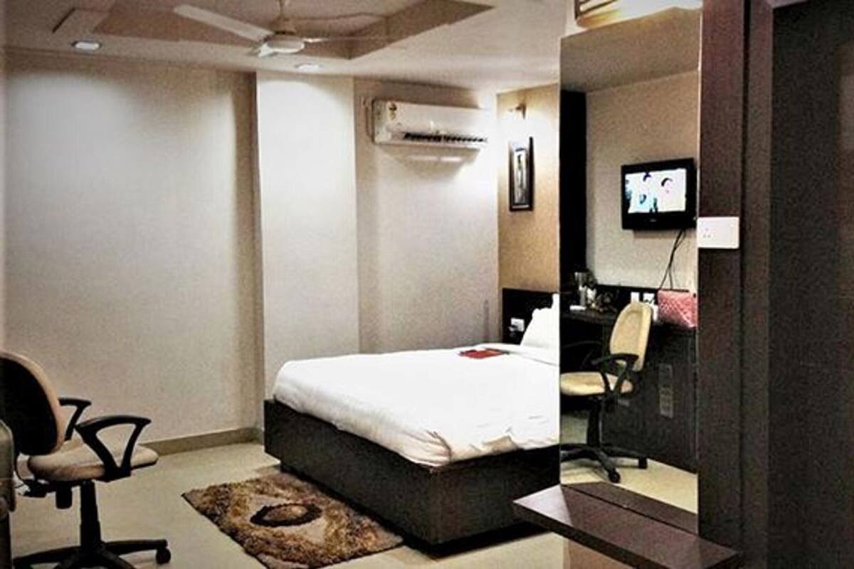 Habitación de hotel con cama, escritorio, silla, aire acondicionado y televisión.