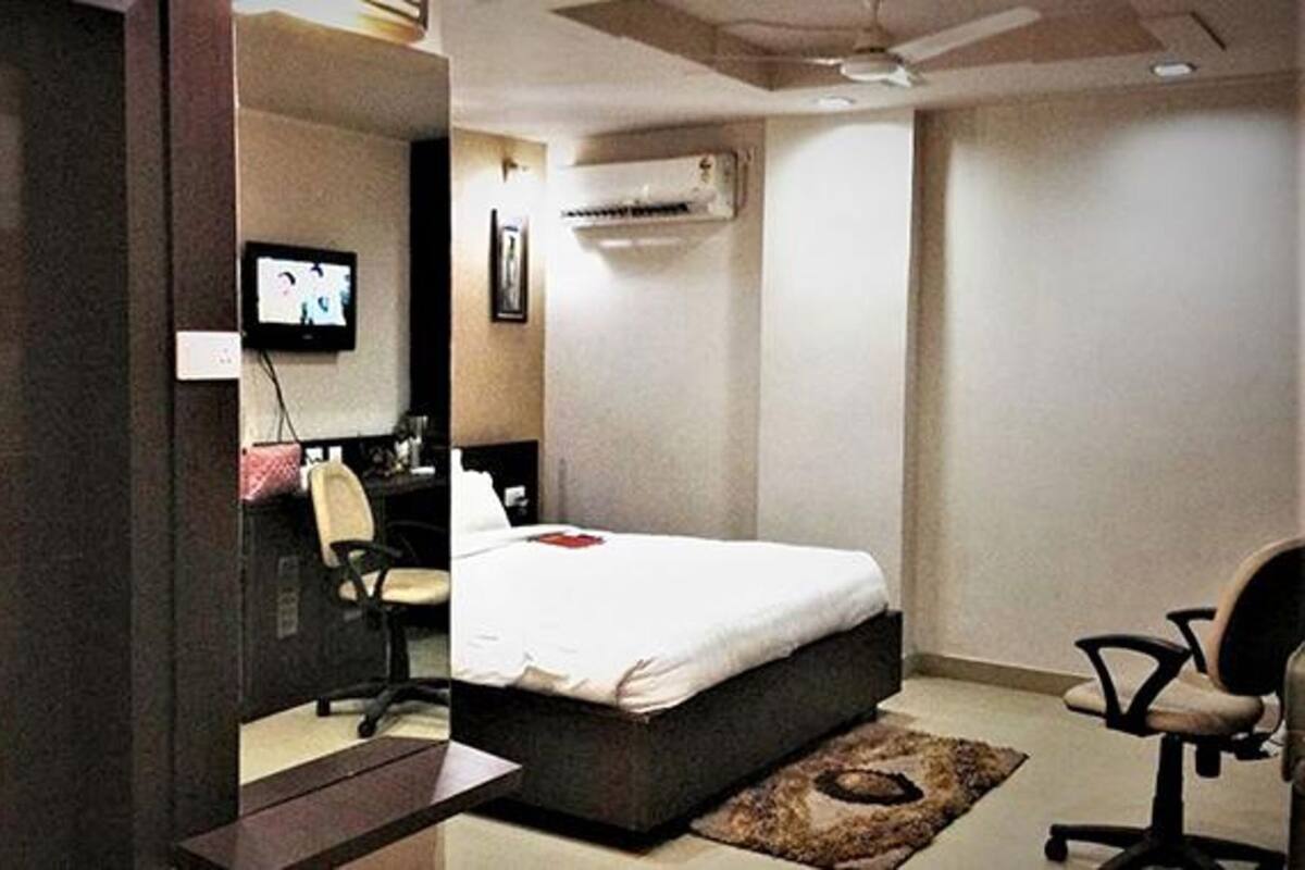 Un dormitorio con una cama, un escritorio, una silla y un equipo de aire acondicionado.