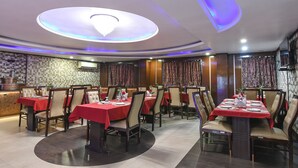 En restaurant med flere spiseborde, med et moderne loftdesign og indbygget belysning.