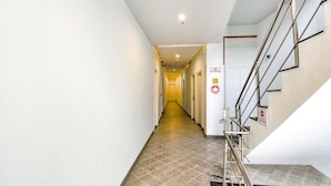 Un couloir d’hôtel avec un sol carrelé, un escalier doté de rampes en métal et un panneau indiquant qu’il est interdit de fumer.