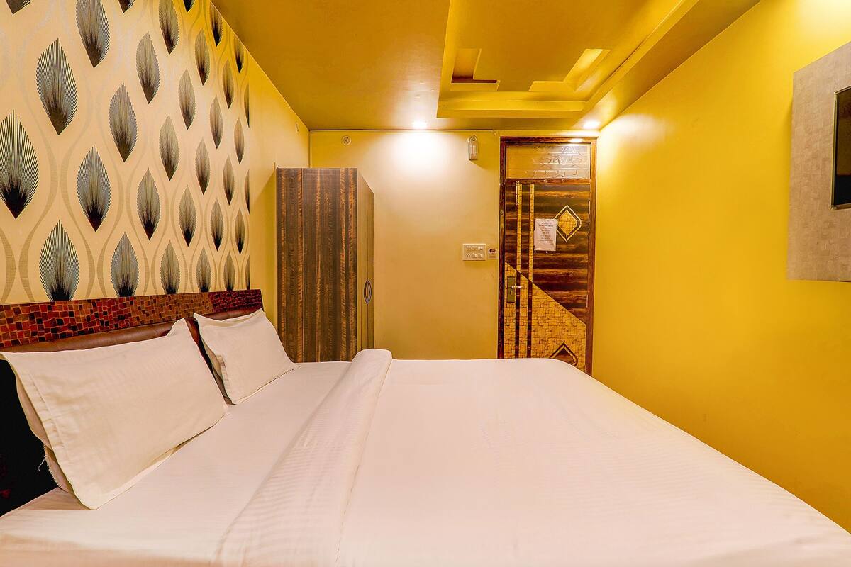 Una habitación de hotel con cama, pared estampada, puerta de madera y una lámpara.