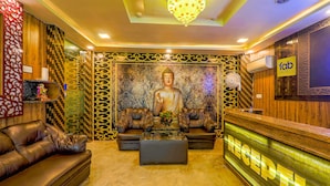 Un espace d’accueil agrémenté d’une statue de Bouddha, de canapés en cuir, d’un comptoir de réception et d’un lustre.