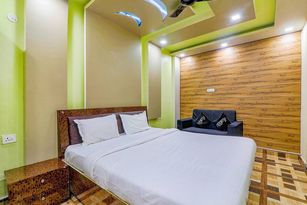 Una habitación de hotel con una cama, una mesita de noche, una silla y un panel de madera decorativo.