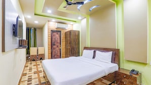 Une chambre d’hôtel avec un grand lit, un ventilateur de plafond, une télévision et un plancher en bois.