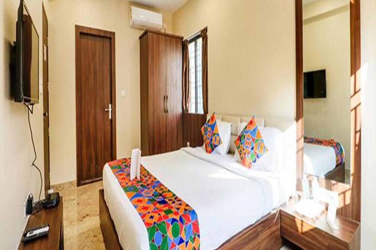 A hotel room with a bed, a TV, a wardrobe, and a mirror.