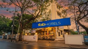 Un hotel llamado 'fab hotels' con un llamativo letrero azul, una entrada con portón y un edificio de varios pisos.