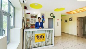 Un mostrador de recepción de hotel con una recepcionista, un reloj y una puerta a la derecha.