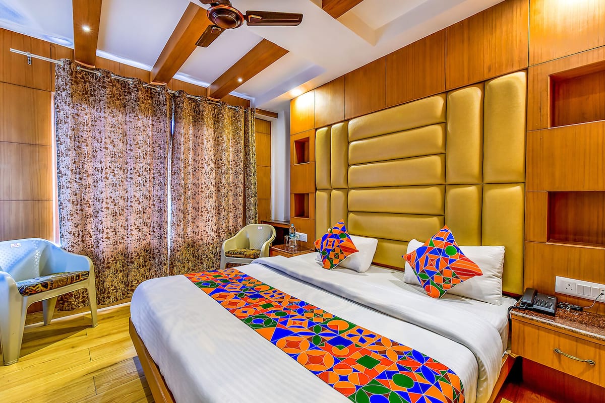 Habitación de hotel con una cama grande, una silla, una mesita de noche, un teléfono y un ventilador de techo.