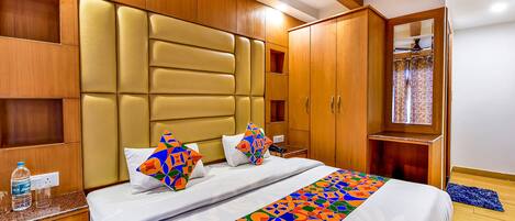 A hotel room with a large bed, wooden headboard, and built-in shelves.