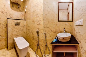 A bathroom with a marble wall, a sink, a mirror, and a toilet. - Fabhotel Clock View - Near clock tower (Dehradun)