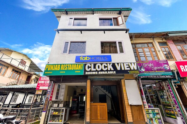 A building with a sign for Fab Hotels, a clock store, and a Punjabi restaurant. - Fabhotel Clock View - Near clock tower (Dehradun)