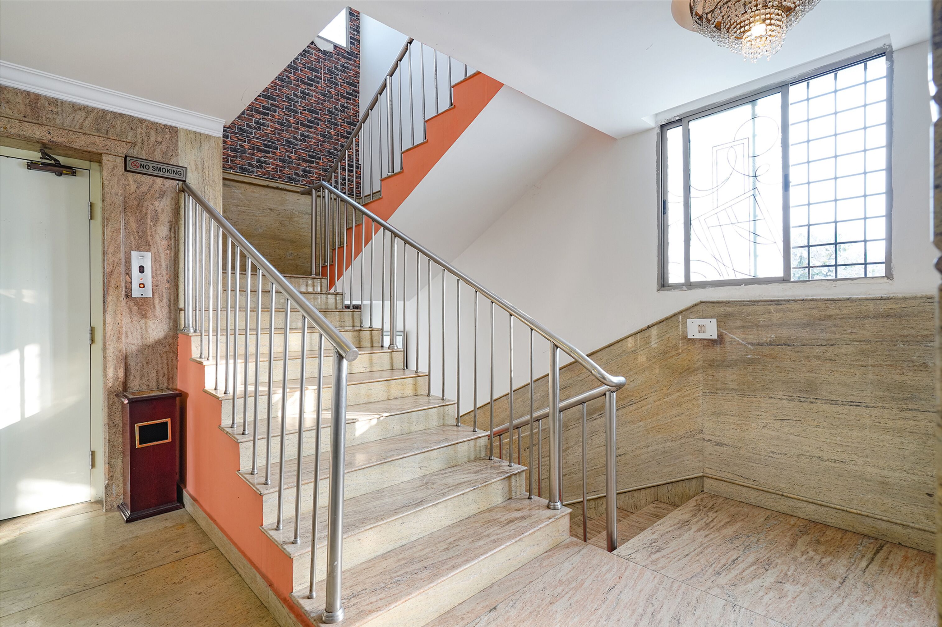 A staircase with metal railings, a brick wall, and a window with a grid pattern.