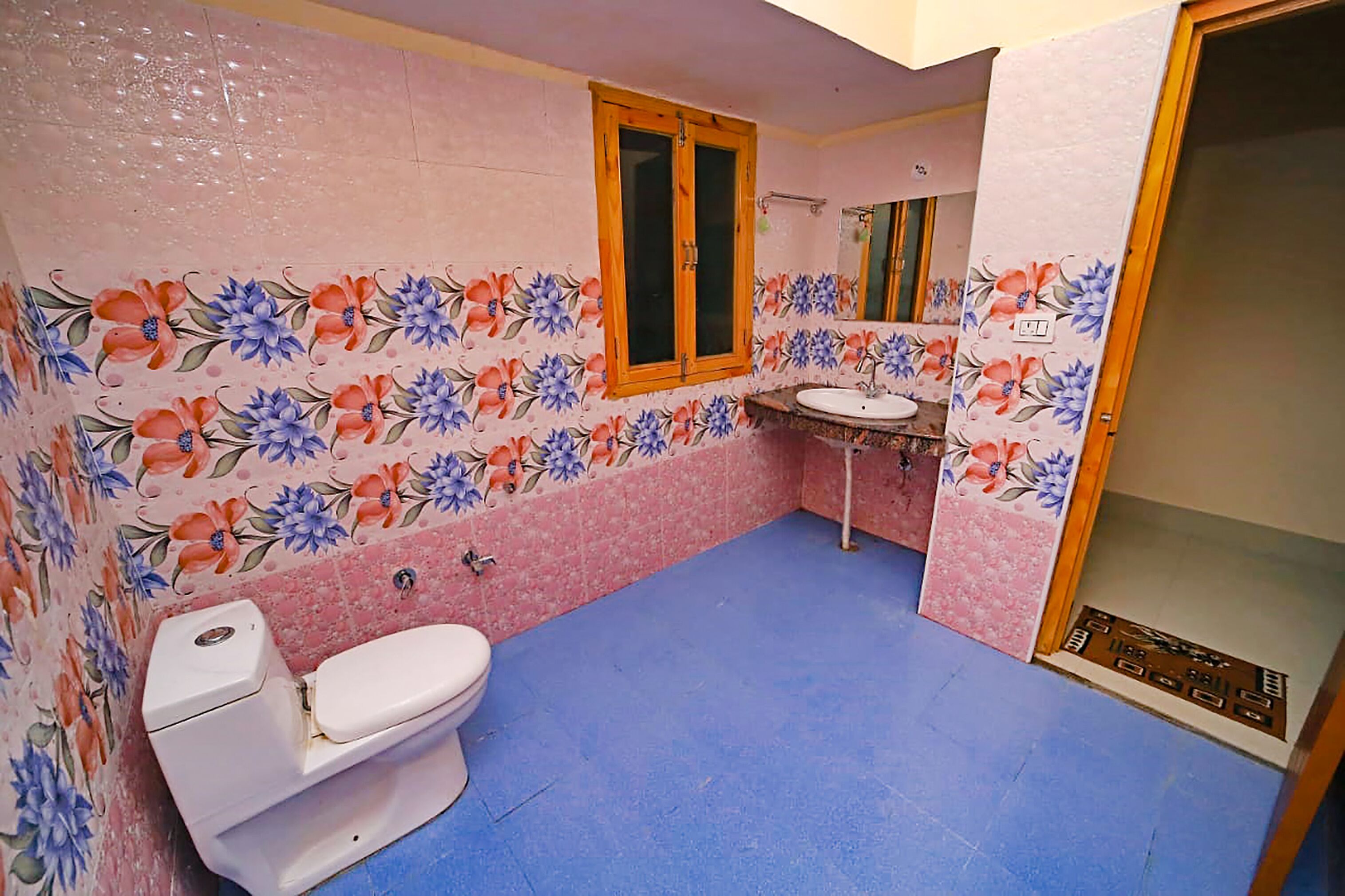 Un baño con azulejos florales, inodoro, lavamanos y zona de ducha.