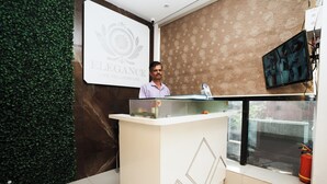 A reception desk with a logo, a water bottle, and a fire extinguisher. - Hotel Elegance (Mumbai)