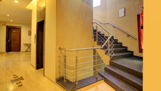 Un vestíbulo de hotel con una escalera, una puerta de madera y una pequeña mesa con una silla.
