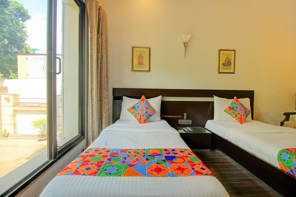 A hotel room with two beds, a large window, and a view of the outside.