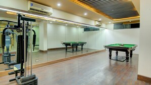 A gym with exercise equipment, a billiards table, and a large mirror. - Fabhotel Staywell (Gurugram)