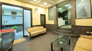 A lobby with a sofa, a glass table, and a reception desk. - Fabhotel Staywell (Gurugram)