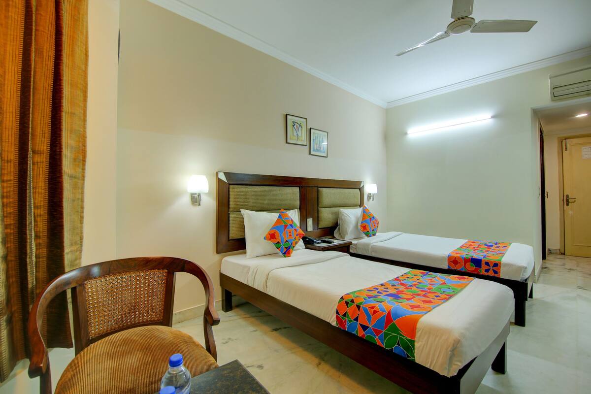 A hotel room with two beds, a chair, a table, and a ceiling fan.