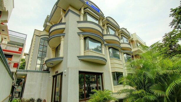 A multi-story building with balconies, large windows, and a well-maintained garden area. - Fabhotel Staywell (Gurugram)